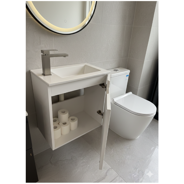 Bathroom with a sink, toilet, and open cabinet revealing toilet paper rolls.